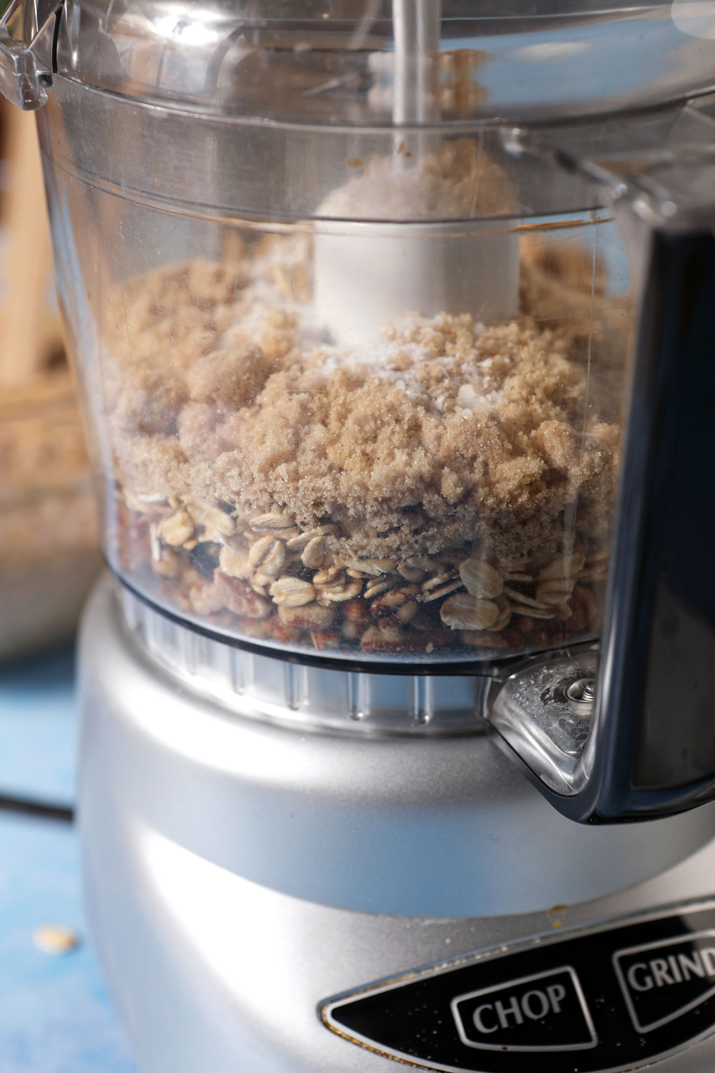 Ingredients to make a streusel topping in a food processor on a blue surface, before blending