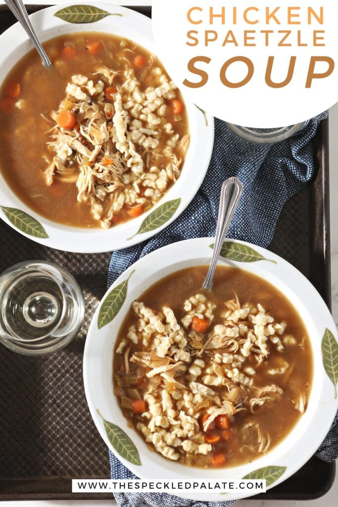 Two white bowls hold chicken soup with German noodles on a metal tray with wine and spoons with the text 'chicken spaetzle soup'