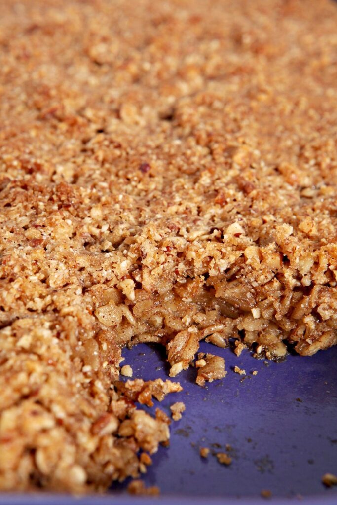 Close up of baked oatmeal in a purple casserole dish after a slice was taken out of it