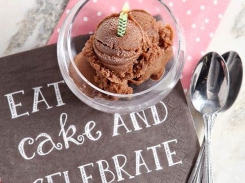Overhead view of chocolate banana ice cream in glass with lit birthday candle
