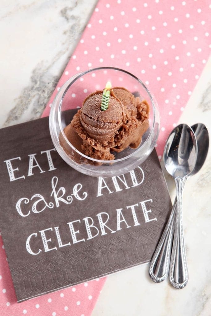 Overhead view of chocolate banana ice cream in glass with lit birthday candle 