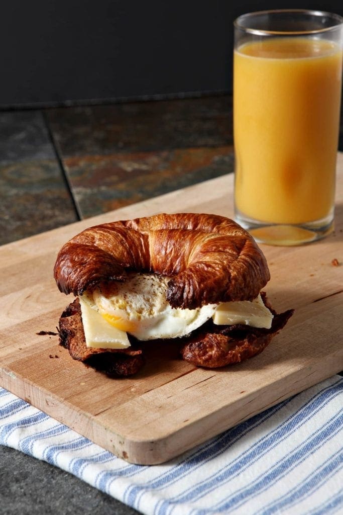 Turkey bacon, sharp cheddar cheese and a fried egg are stacked in a croissant to make the BEST breakfast sandwich for this new year!