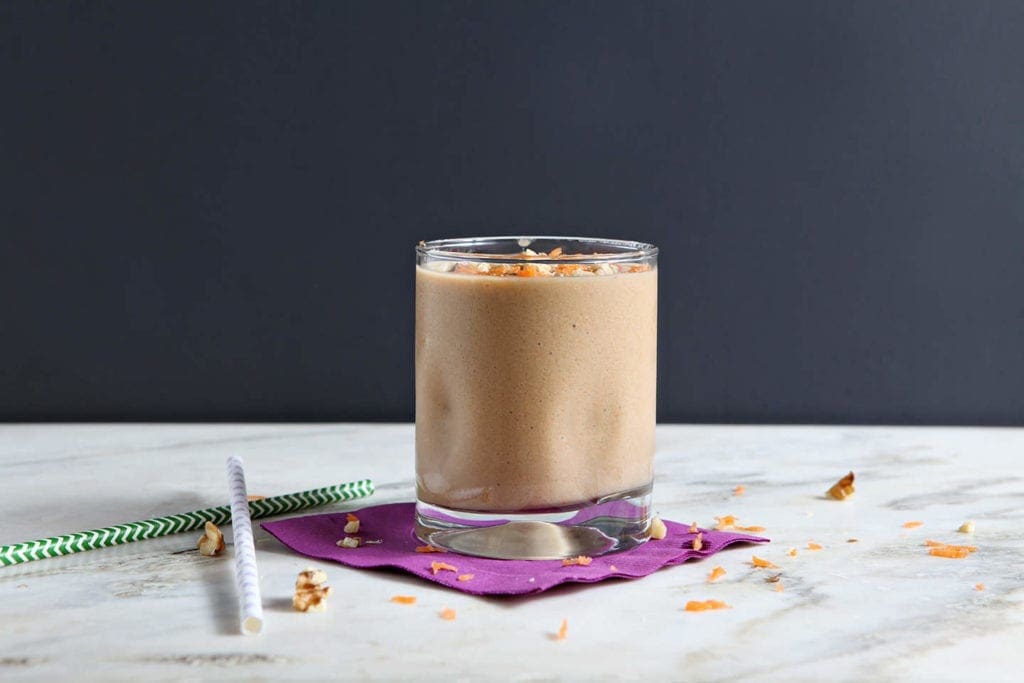 Glass of vegan carrot cake smoothie on purple napkin 