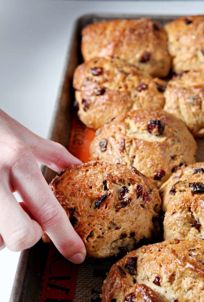 Close up of hand picking up fruit bun from baking sheet 