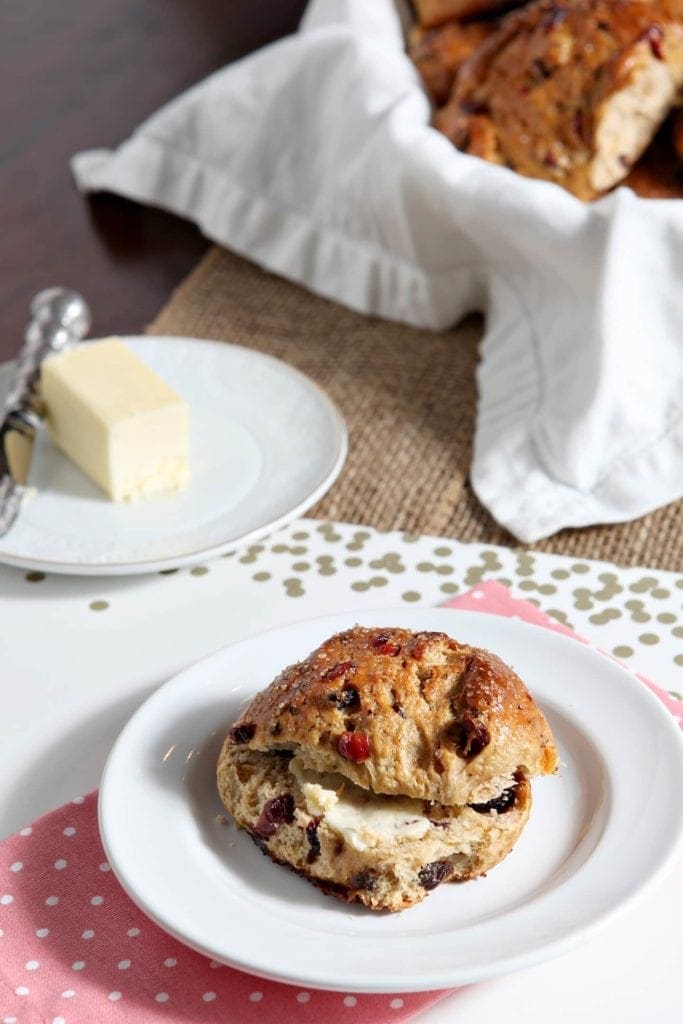 Sliced fruit bun with butter on white plate