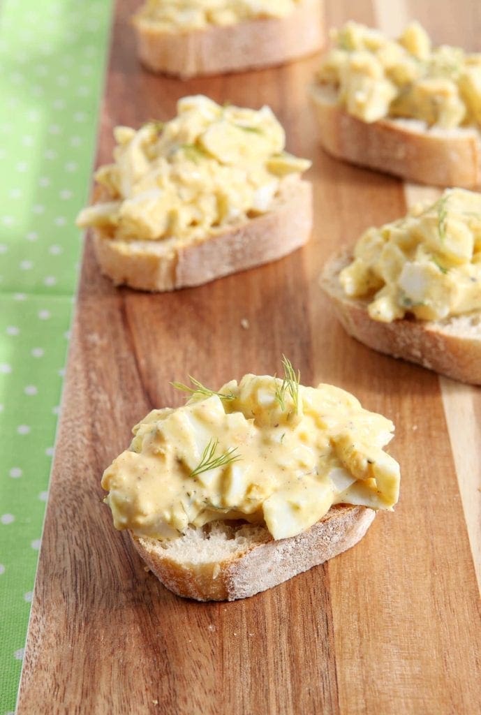 Deviled Egg bruschetta is displayed on a wooden platter