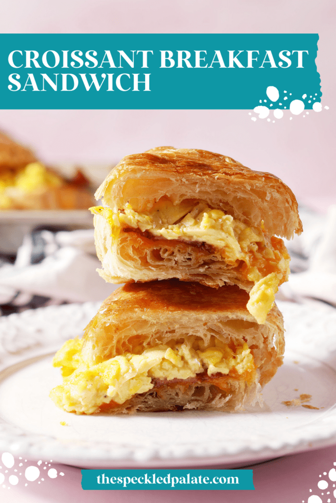 a halved breakfast sandwich with eggs stacked on top of itself on a white plate with the text croissant breakfast sandwich