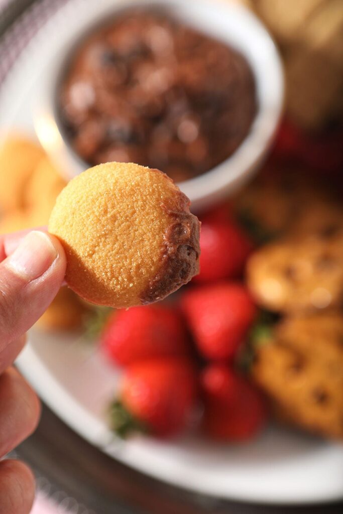 A nilla wafer dipped in chocolate is held above a platter with dippers