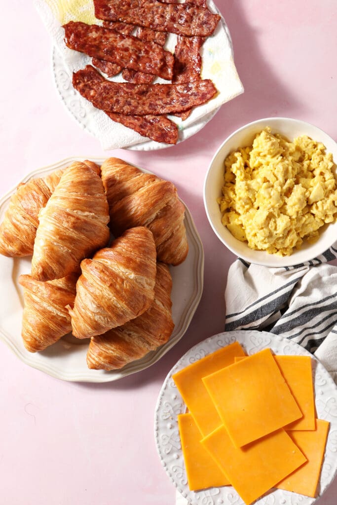 ingredients to make breakfast sandwiches with croissants with the eggs and bacon cooked