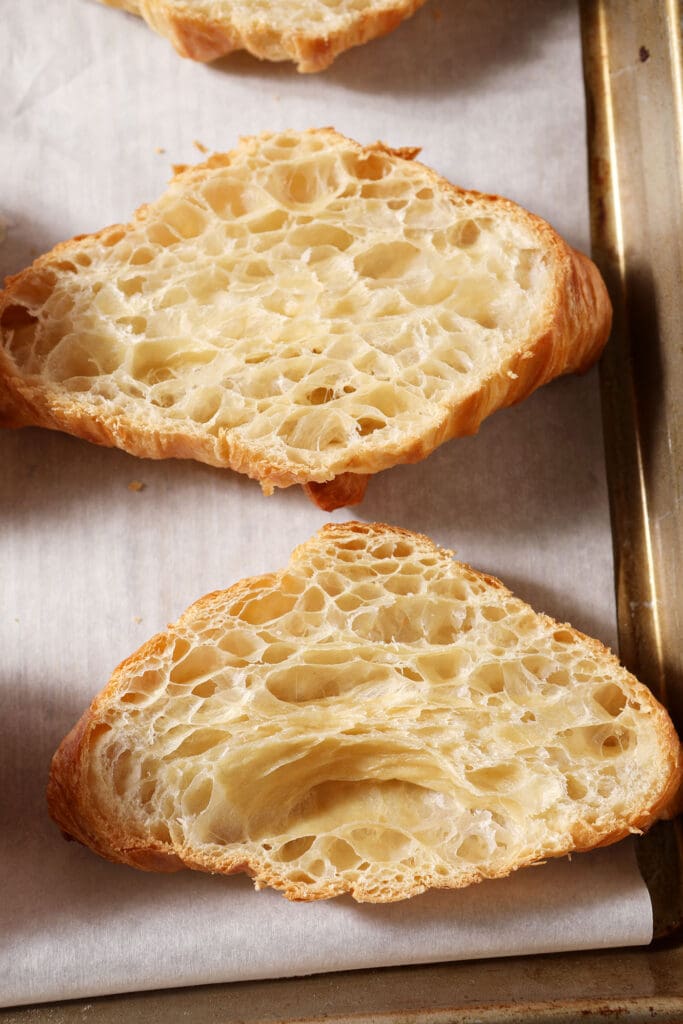 halved croissants on a sheet pan before toasting