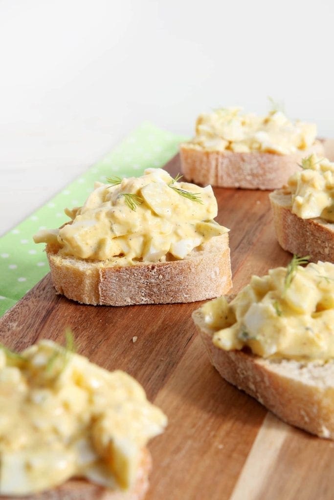 Angled view of Deviled Egg Bruschetta sitting on wood board 