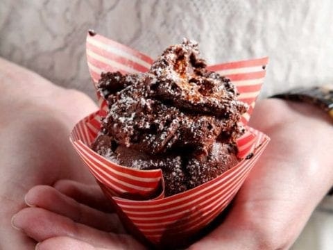 Hands holding sweet and spicy chocolate cupcake in striped wrapper