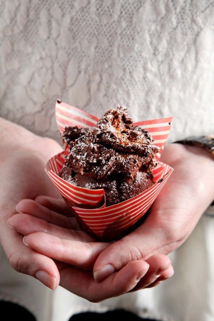 Hands holding sweet and spicy chocolate cupcake in striped wrapper 