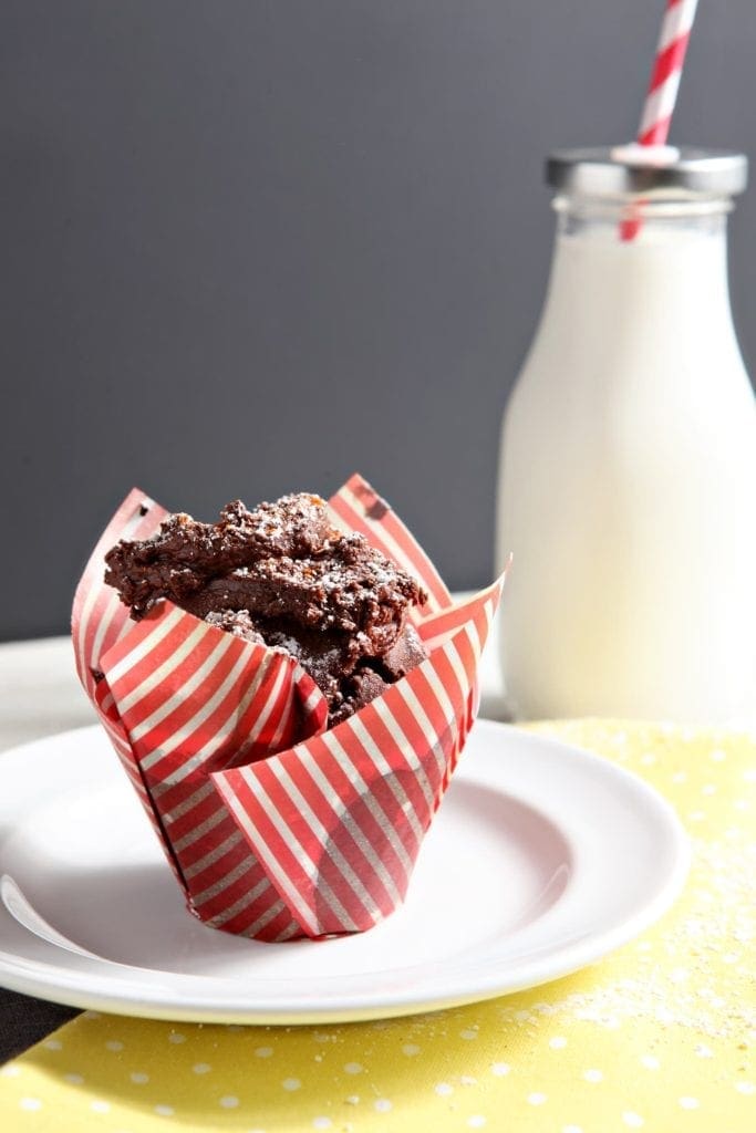 Sweet and spicy chocolate cupcake in striped wrapper on white plate 