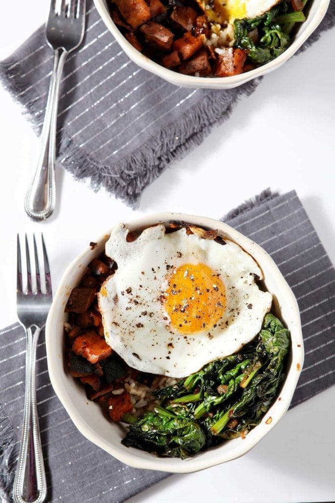 Overhead view of curried veggie rice bowls with forks on linens 