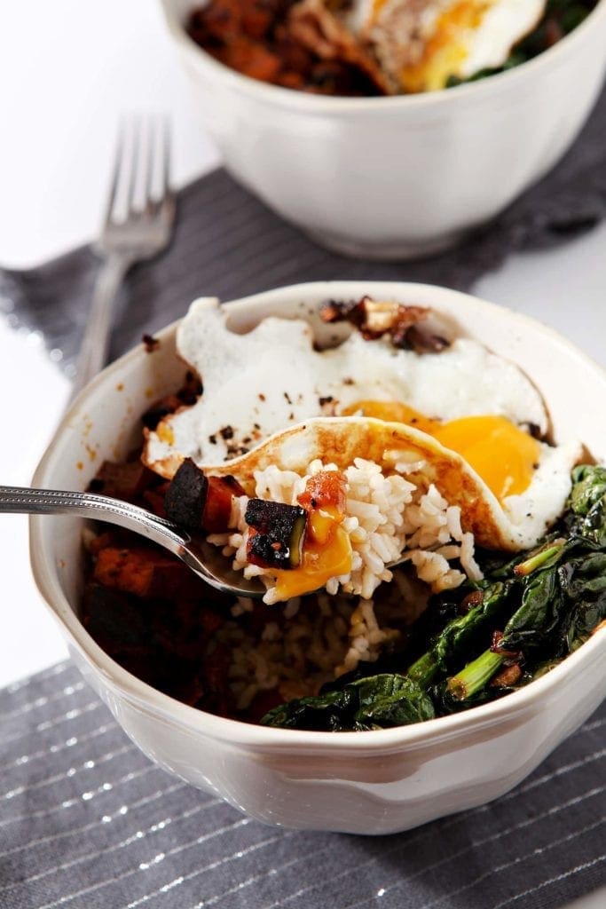 Fork pulling out curried veggie rice from white bowl 