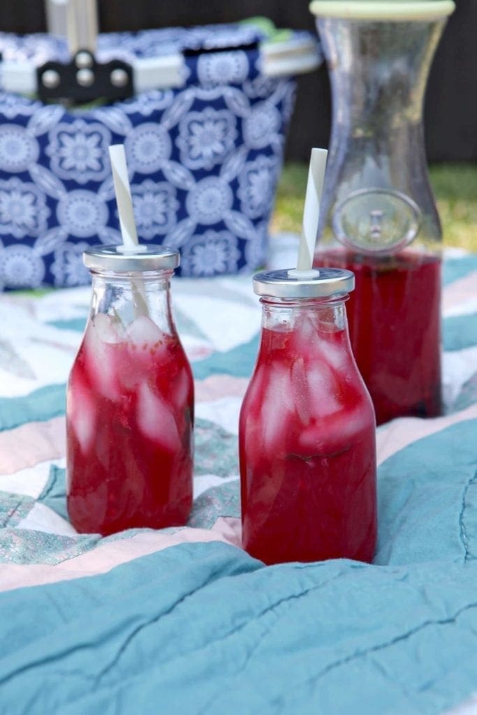 Two bottles of Mixed Berry Mint Lemonade on top of picnic blanket