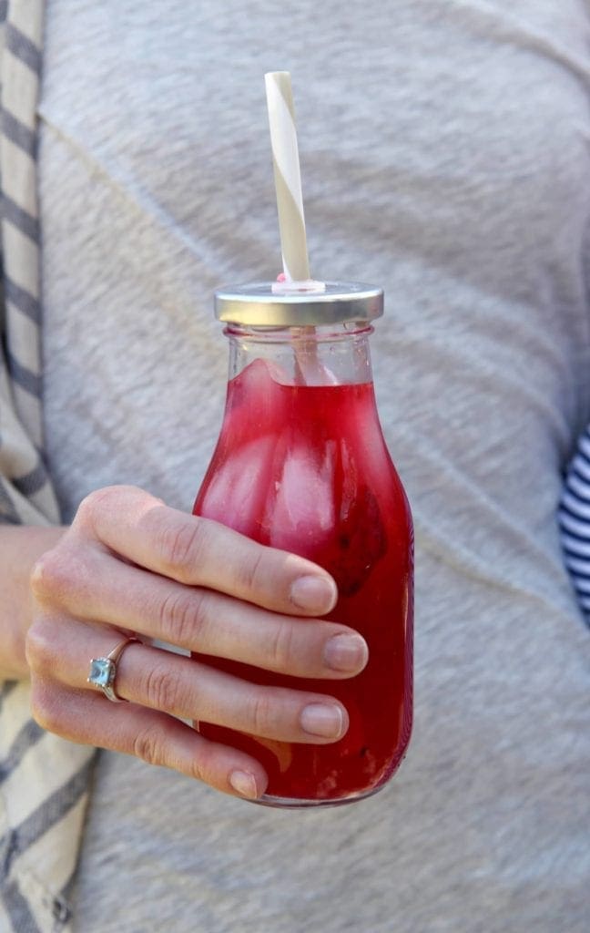 Hand holding glass jar with straw of mixed berry mint lemonade 