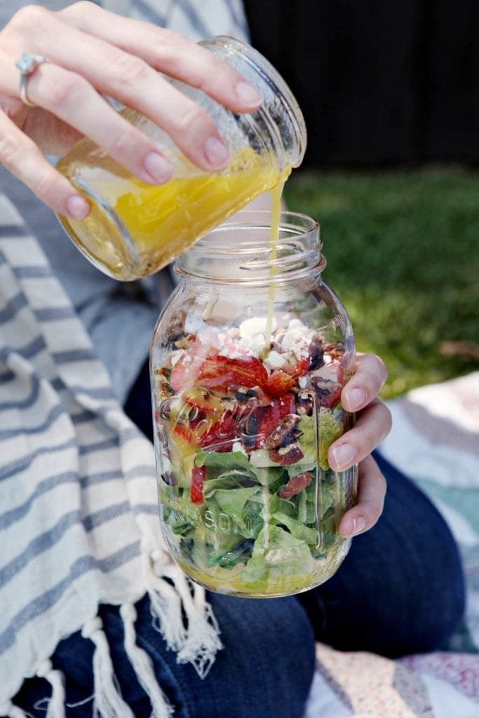 pouring dressing in a jar with strawberry romaine salad