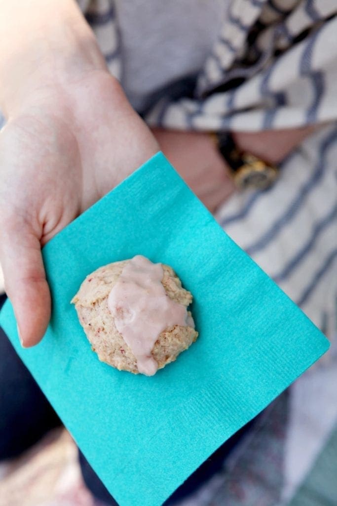 Hand holding strawberry lemonade cookie on teal napkin 