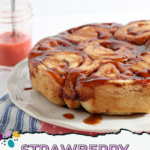 Baked strawberry cinnamon bun on white serving dish with drizzled glaze