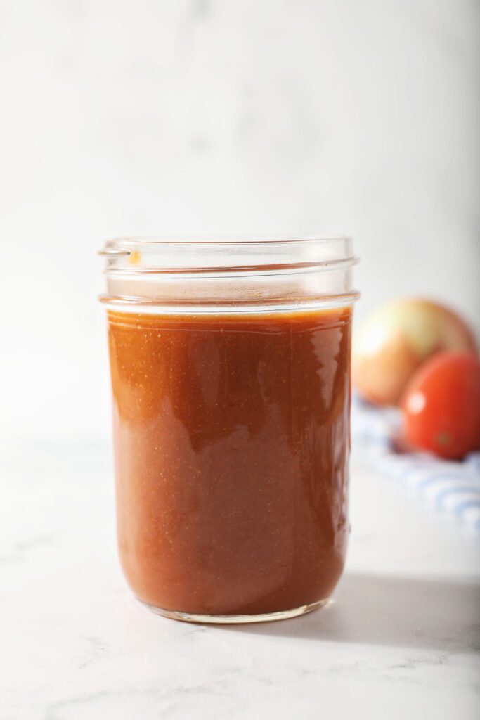 A jar of homemade enchilada sauce on marble