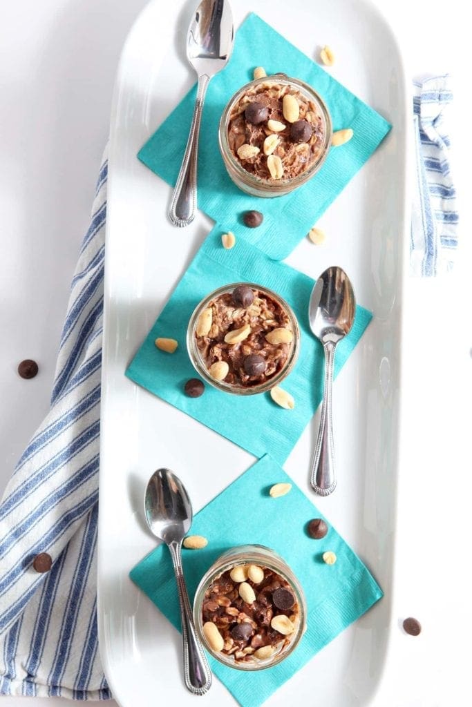 Overhead view of three glass jars of peanut butter chocolate oats on serving dish 