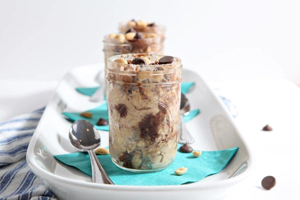 Peanut Butter Chocolate Chip Oats in glass jars on white serving dish 