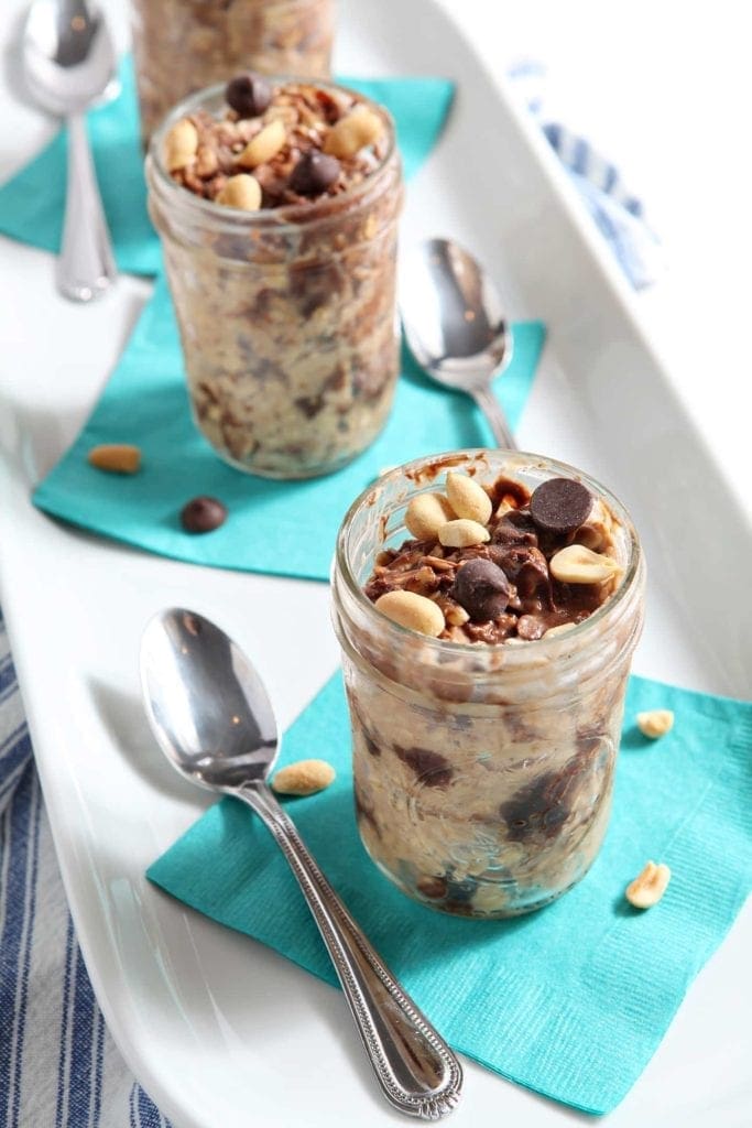 Overhead angled view of peanut butter chocolate chip oats in 3 glass jars 