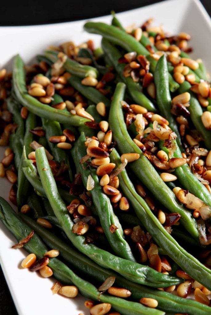 Close up of Toasted Pine Nut Green Beans, served on a white platter