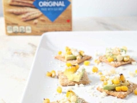 Crackers with toppings on platter in front of box of crackers 