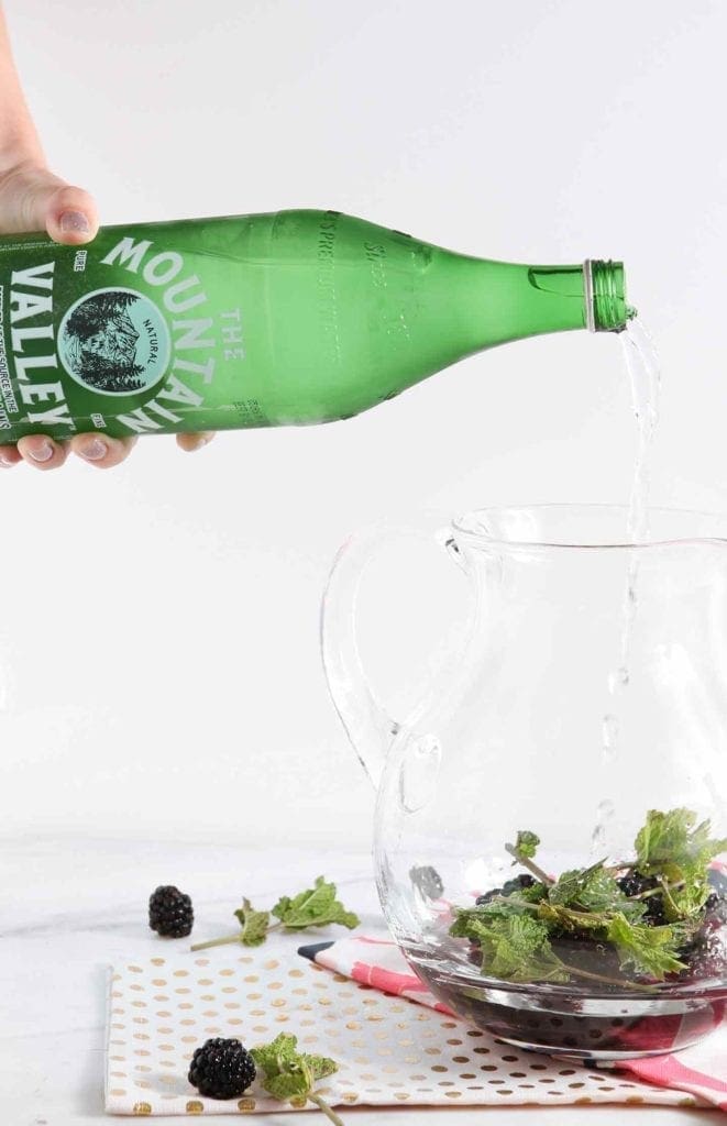 Water pouring in a pitcher of blackberries and mint 