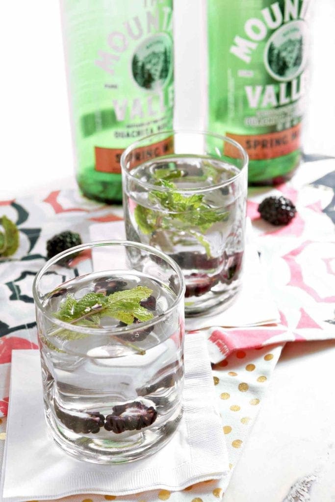 Two glasses of blackberry mint spa water on decorative napkins 