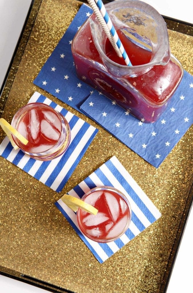 Overhead view of 2 glasses and pitcher of cherry lemon tea on napkins 