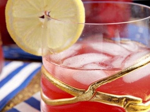 Glass of cherry lemon tea with slice of lemon
