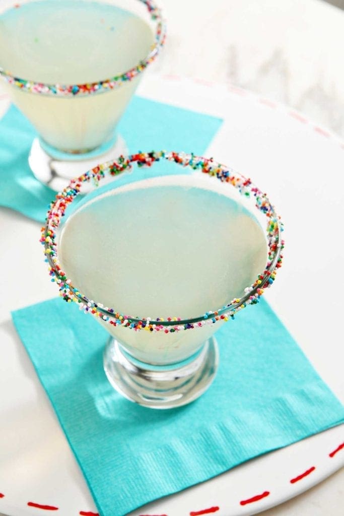 Funfettini Birthday Cake Martini with garnished rim on teal napkin 