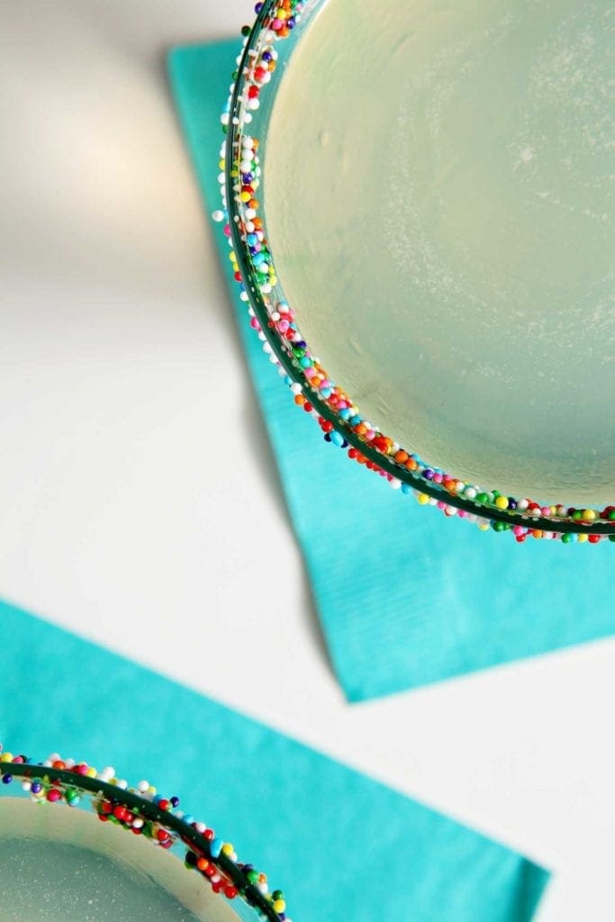 Close up of rainbow nonpareil garnish on martini glass rim 