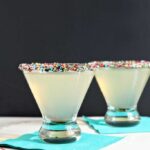 Two glasses of Funfettini Birthday Cake Martinis on teal napkins