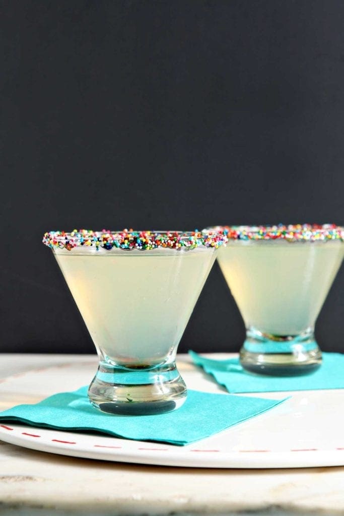 Two glasses of Funfettini Birthday Cake Martinis on teal napkins