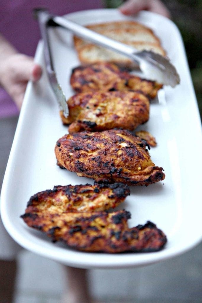 White platter of grilled chicken shawarma with tongs 