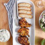 Grilled Chicken Shawarma on serving dish with sides on wood table