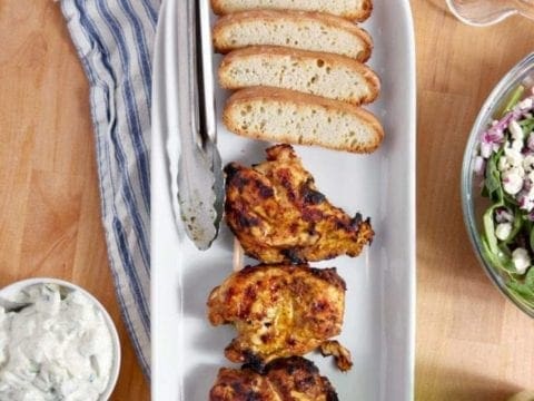 Grilled Chicken Shawarma on serving dish with sides on wood table