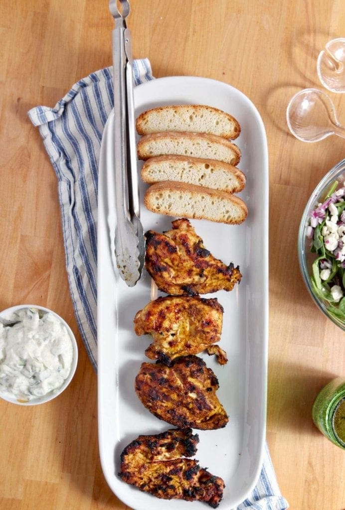 Grilled Chicken Shawarma on serving dish with sides on wood table 