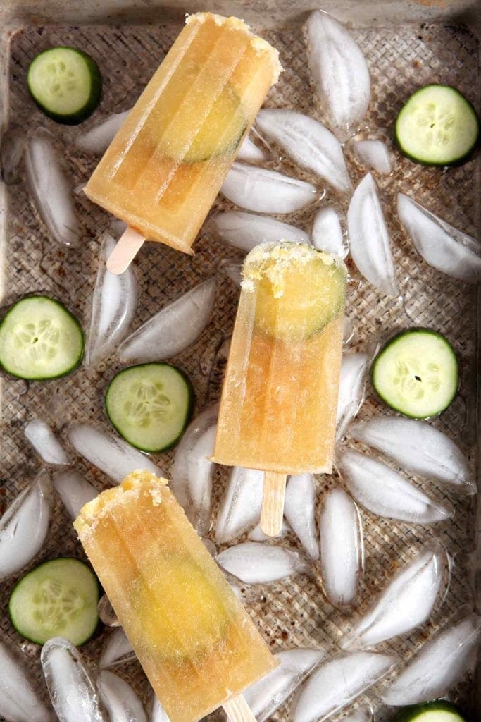 Three popsicles on top of ice cubes and slices of cucumber 