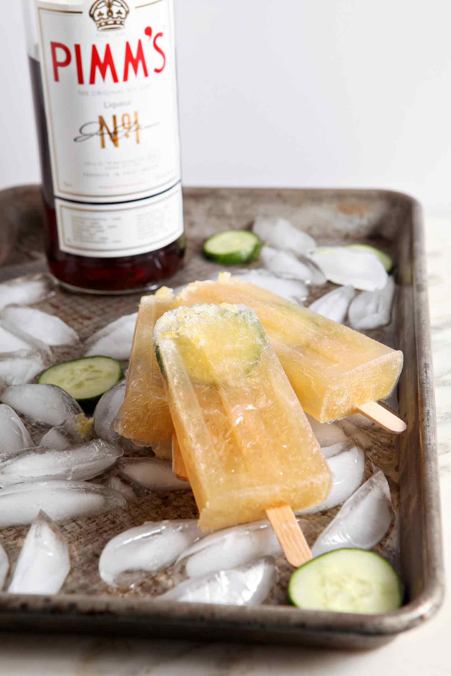 Popsicles stacked on top of tray with ice and sliced cucumber 