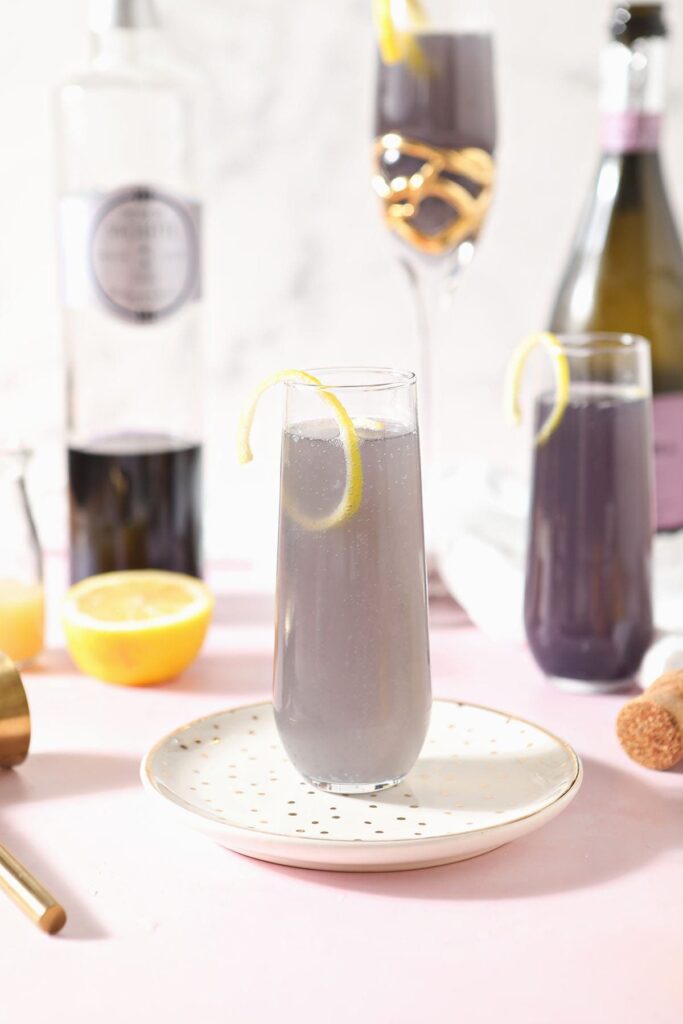 A creme de violette drink sits on a gold plate