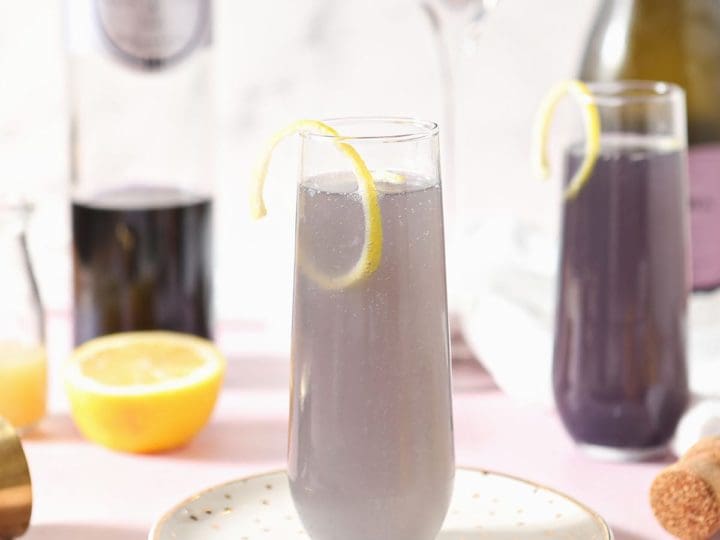 A creme de violette drink sits on a gold plate