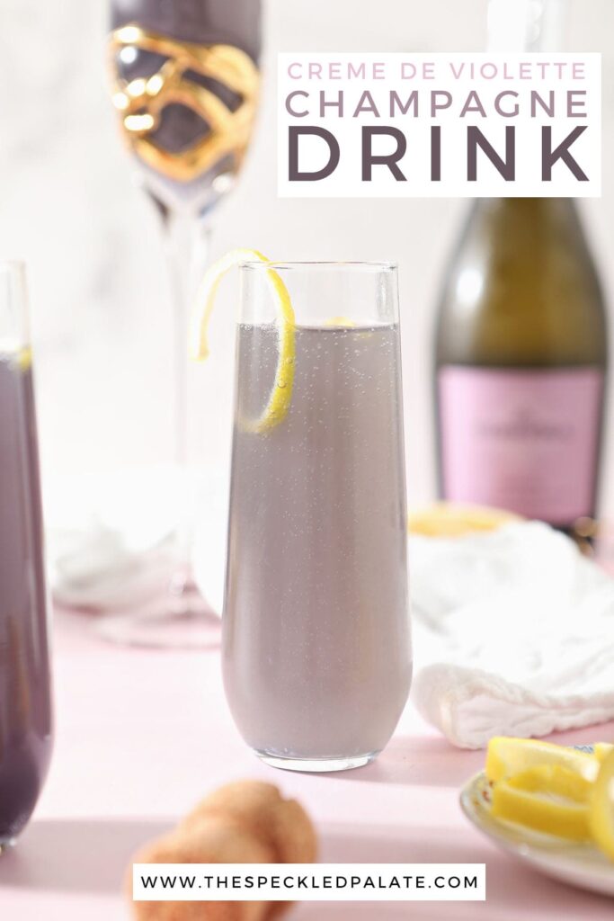 A champagne flute holds a purple drink garnished with a lemon twist with the text 'creme de violette champagne drink'