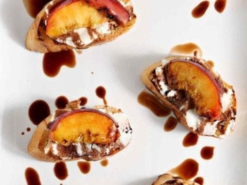 Grilled Peach Bruschetta is a perfect sweet appetizer or dessert for the summertime. Fire up the grill, slice and pit a few fresh peaches, brush the peaches with a little bit of olive oil, then grill until the sugars in the fruit caramelizes. Grill the bread, too. When both are done, smear the bread with fresh ricotta cheese, place the peach slices on top of the cheese, then drizzle with a balsamic vinegar reduction for the final touch. Perfect!