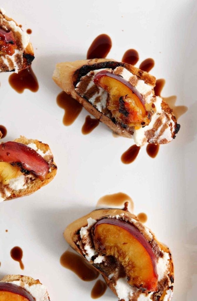 Grilled Peach Bruschetta is a perfect sweet appetizer or dessert for the summertime. Fire up the grill, slice and pit a few fresh peaches, brush the peaches with a little bit of olive oil, then grill until the sugars in the fruit caramelizes. Grill the bread, too. When both are done, smear the bread with fresh ricotta cheese, place the peach slices on top of the cheese, then drizzle with a balsamic vinegar reduction for the final touch. Perfect!